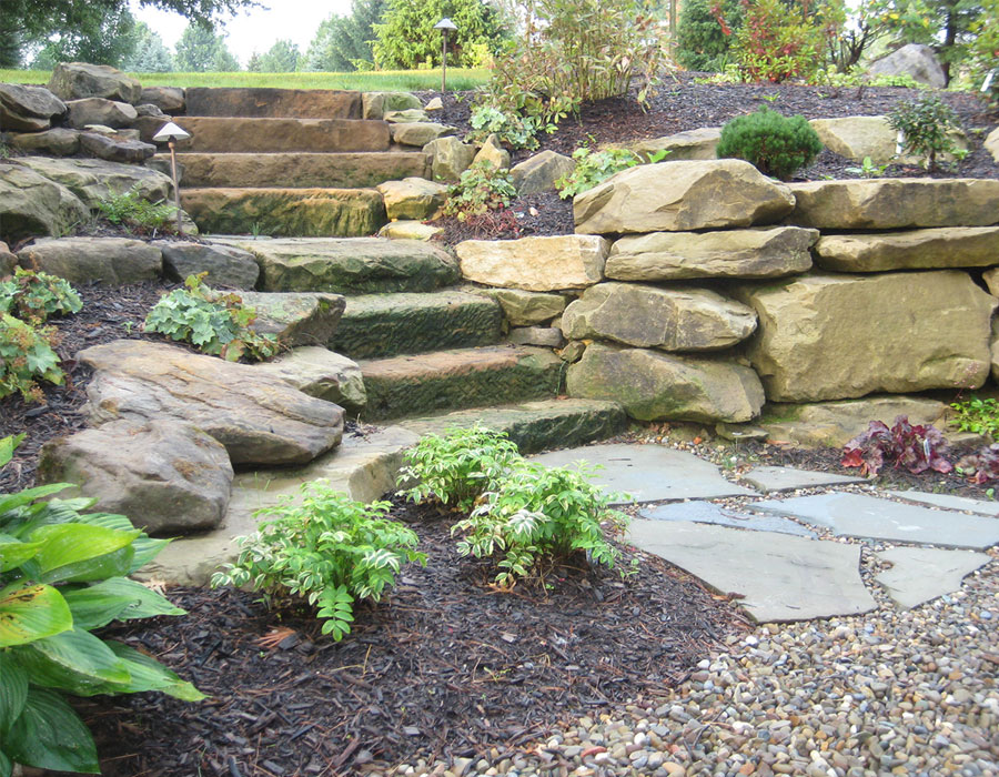 Madison Ohio home with exterior barnstone outcropping garden wall and natural stone steps