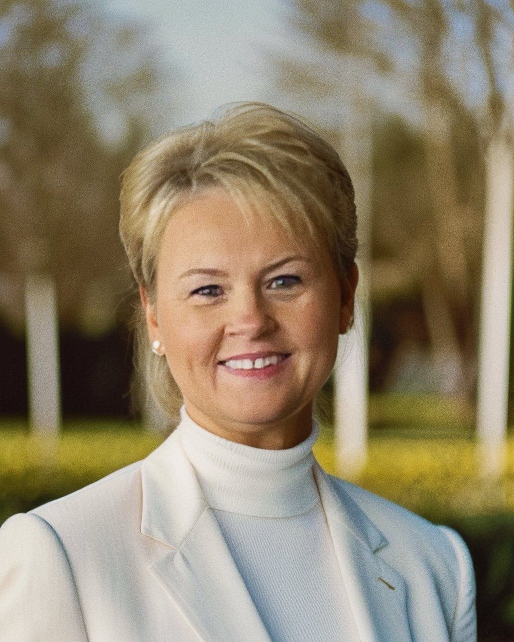 a woman wearing a black jacket and a white shirt smiles for the camera