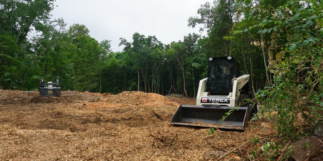 backhoe sitting in plot of deforested land