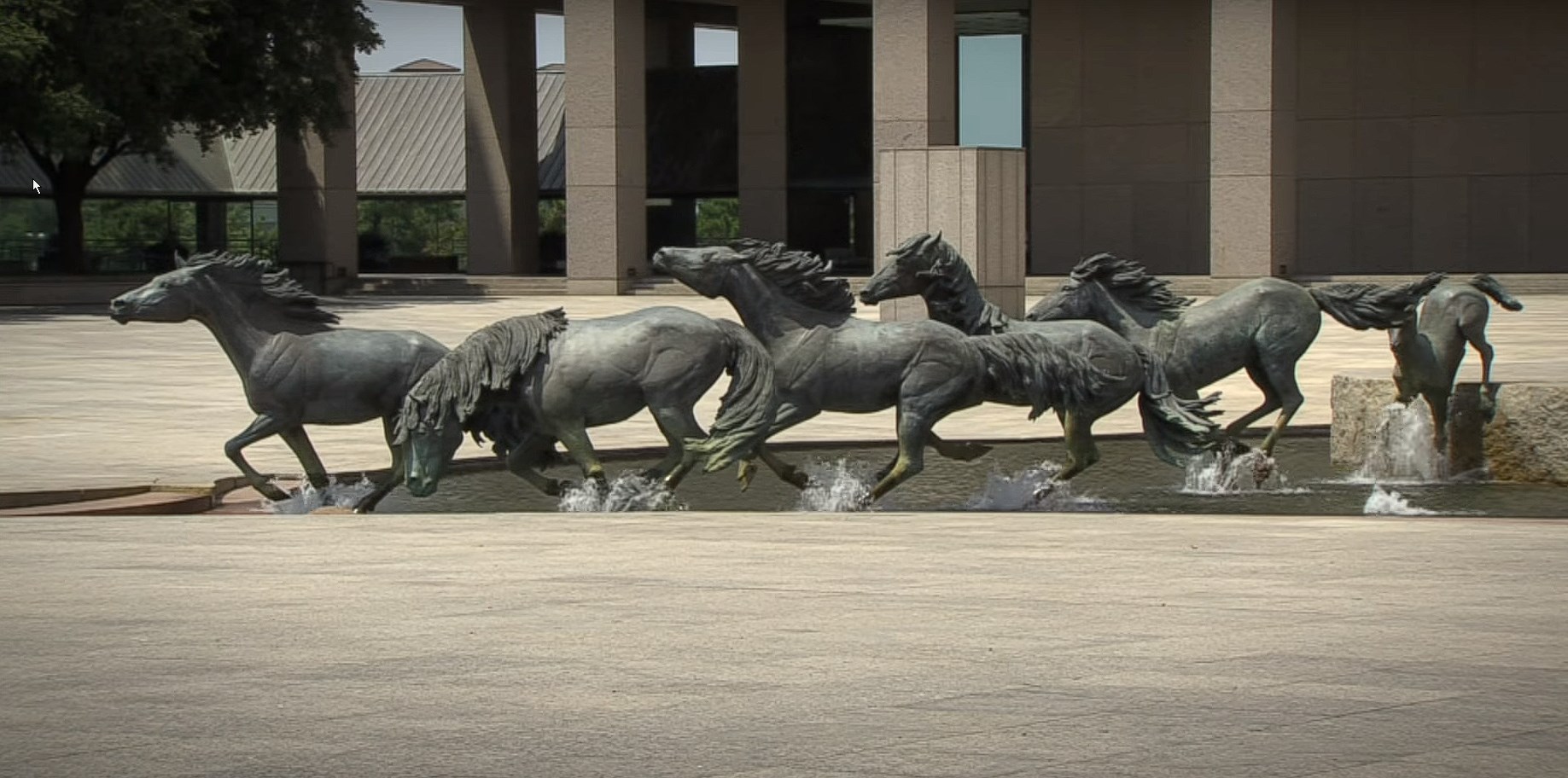 Mustangs of Las Colinas horse sculptures running through water in Irving, TX