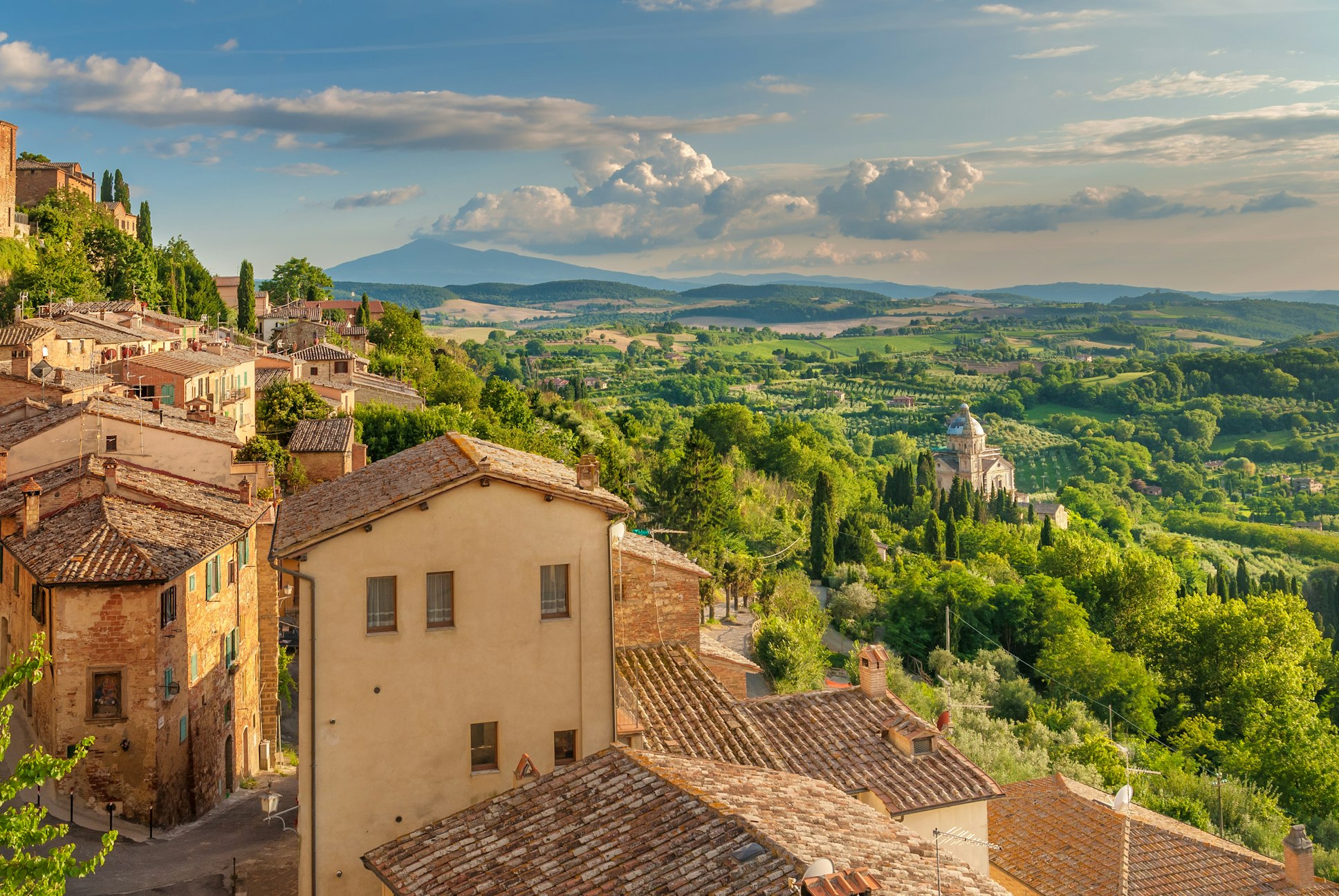 View of rolling hills, vineyards, and historic buildings in Tuscany, Italy.