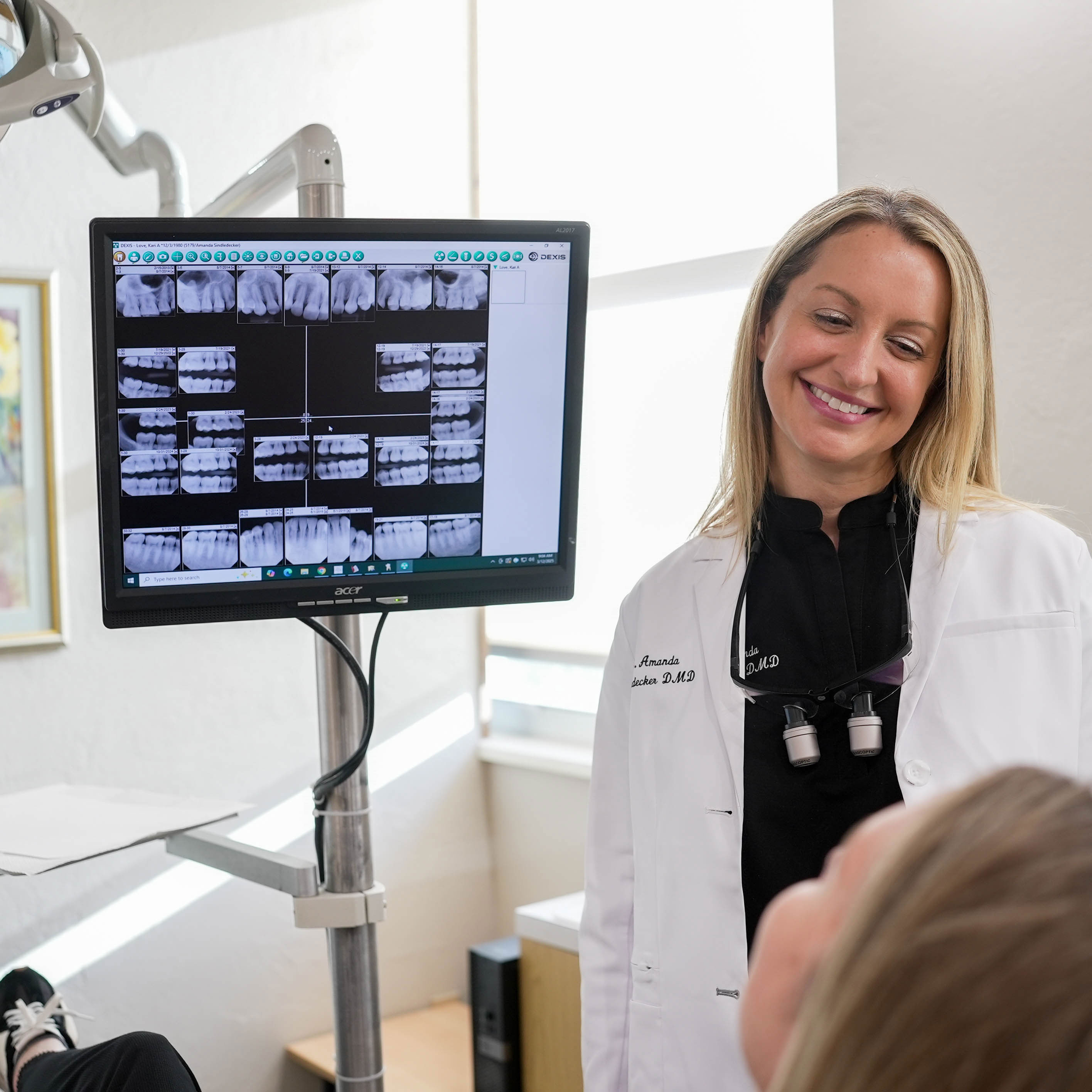 A man with a beard is wearing a white shirt and smiling with his arms crossed.