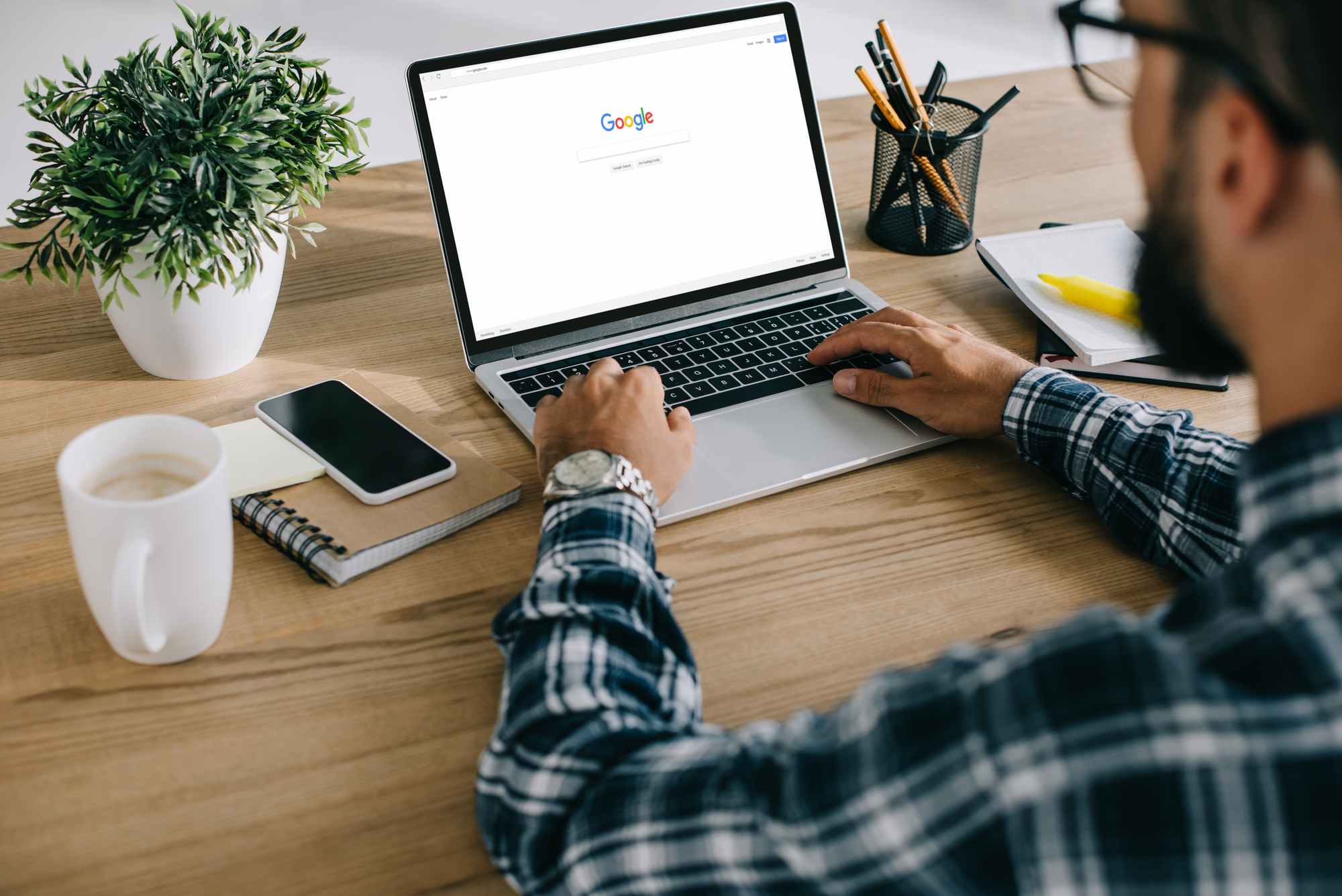 man searching Google on a laptop sitting at a desk