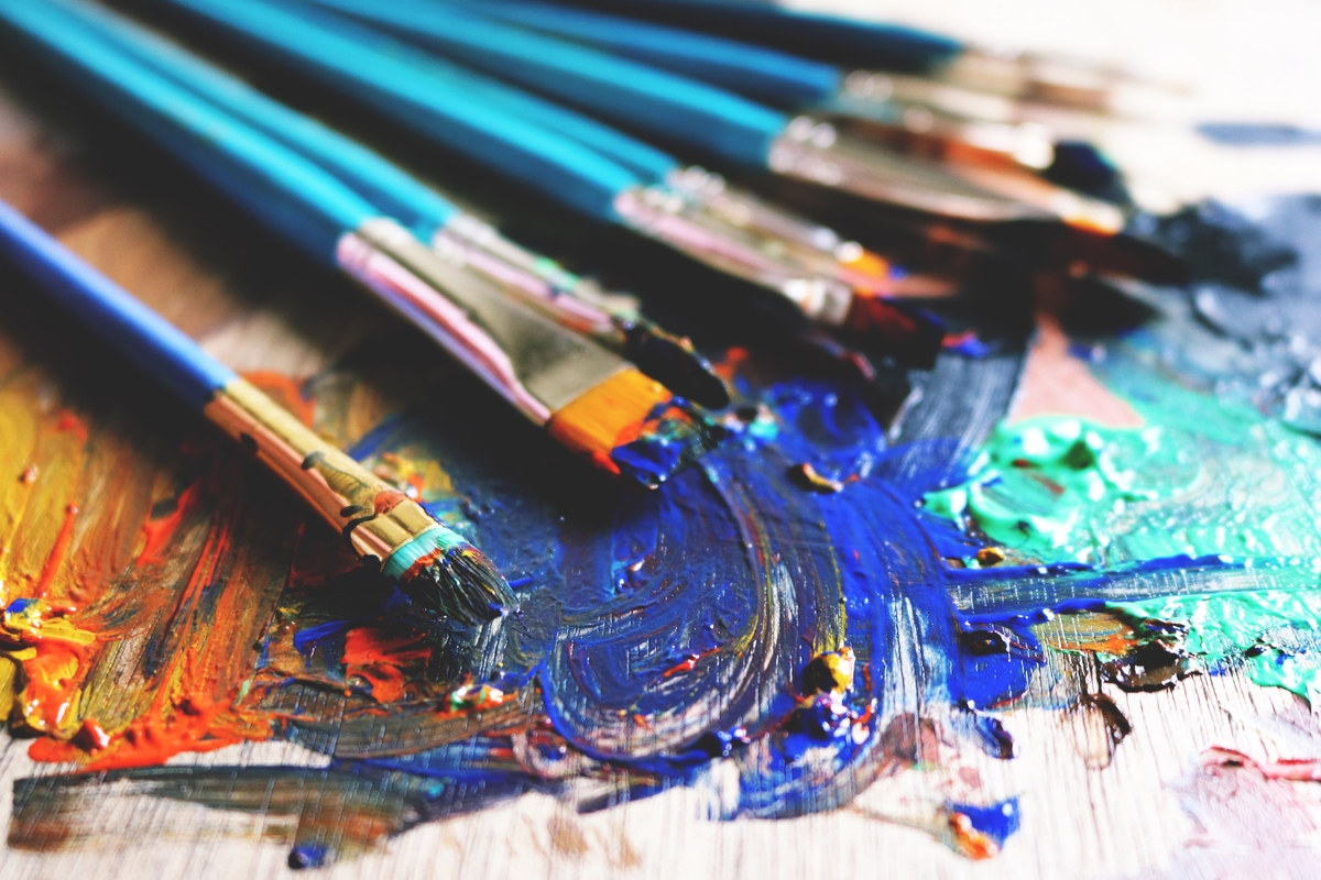 Paint brushes covered in blue and green paint on wood