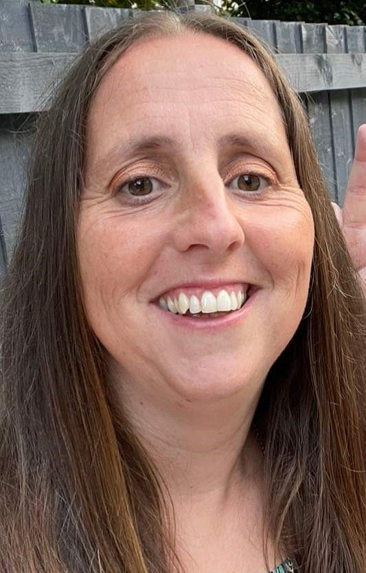 a lady called zoe hawken sat down in front of a garden fence smiling and having fun