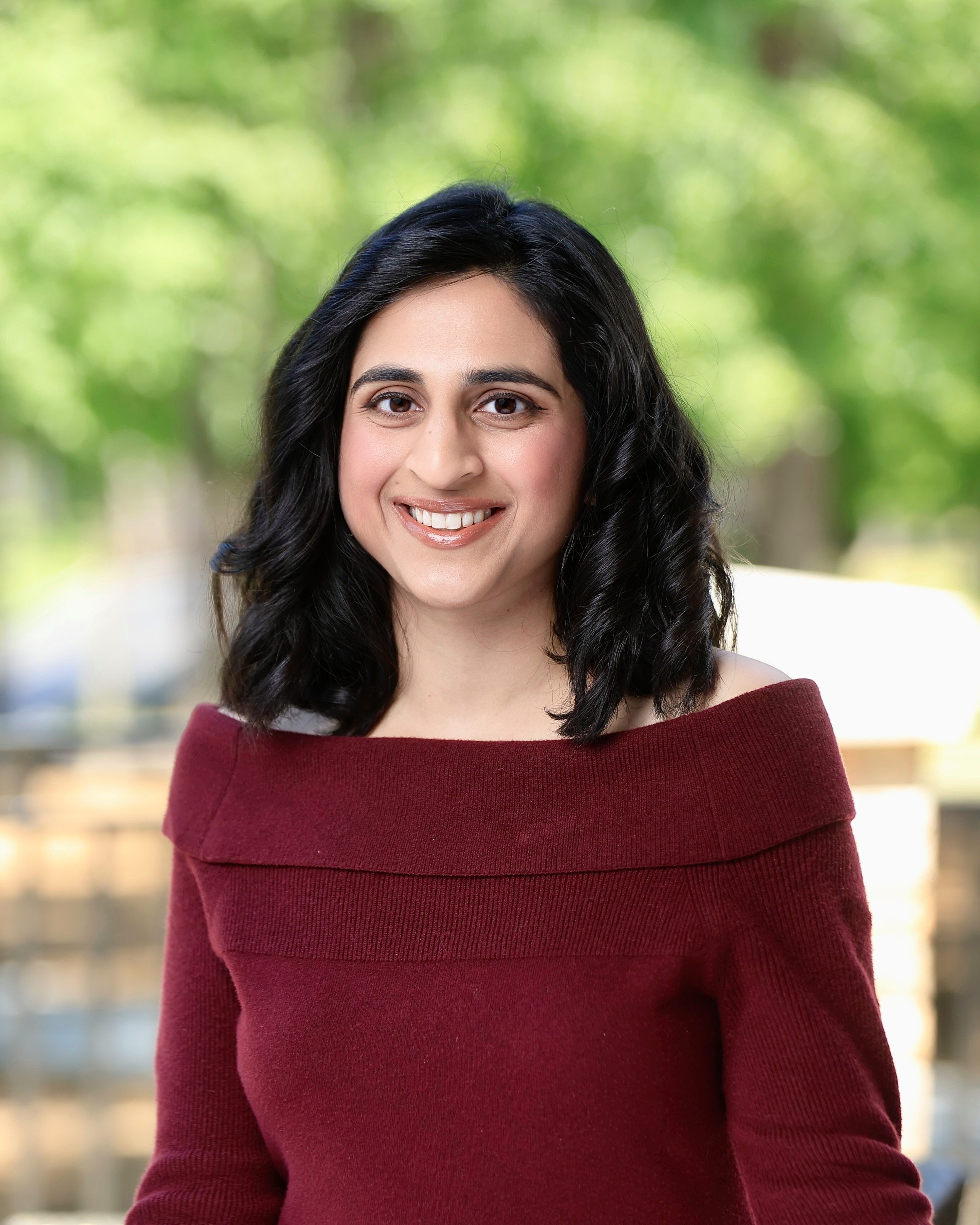 a woman wearing a black jacket and a red scarf is smiling for the camera .