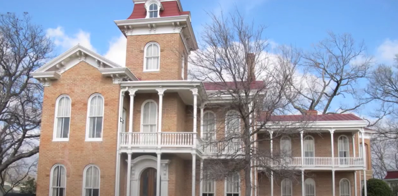 Historic Waco brick mansion with a tower and multiple porches