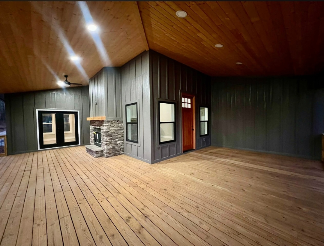 Covered deck and outdoor living space with wood flooring, ceiling, and fireplace built by Foothills Construction and Restoration Services in Morganton, NC. Call (828) 373-1194.
