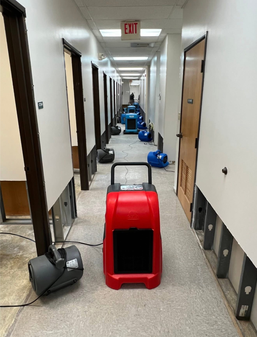 Commercial hallway water damage drying with industrial dehumidifiers and air movers by Foothills Construction and Restoration Services, call (828) 600-5227.