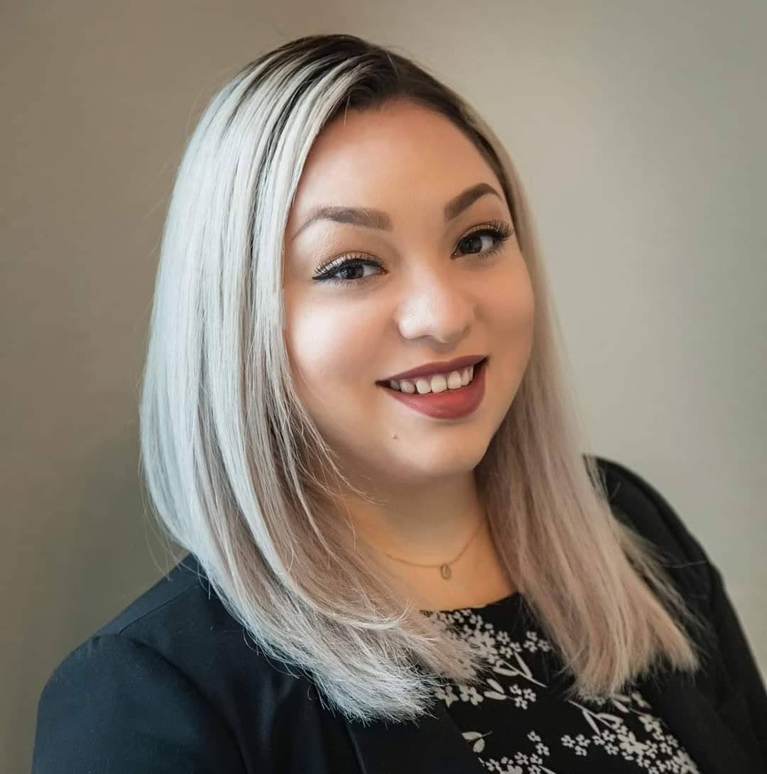 a woman wearing a black jacket and a red scarf is smiling for the camera .