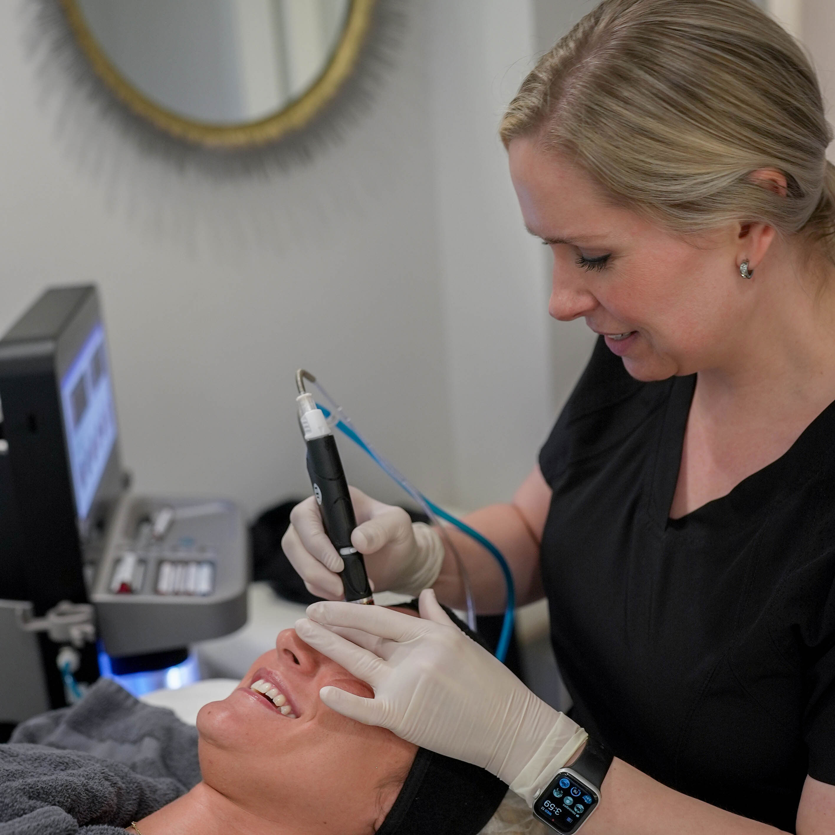 A man with a beard is wearing a white shirt and smiling with his arms crossed.