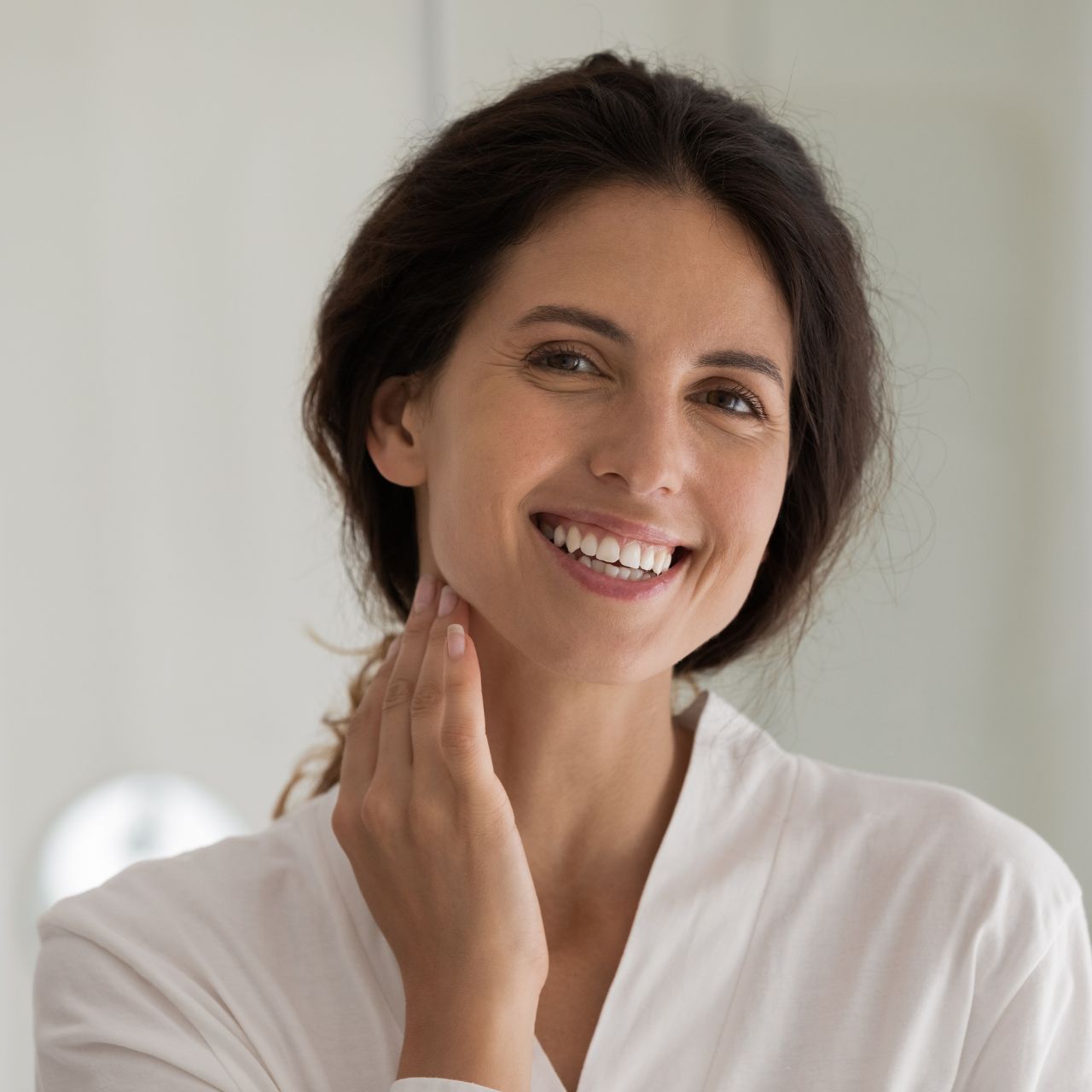 A man with a beard is wearing a white shirt and smiling with his arms crossed.