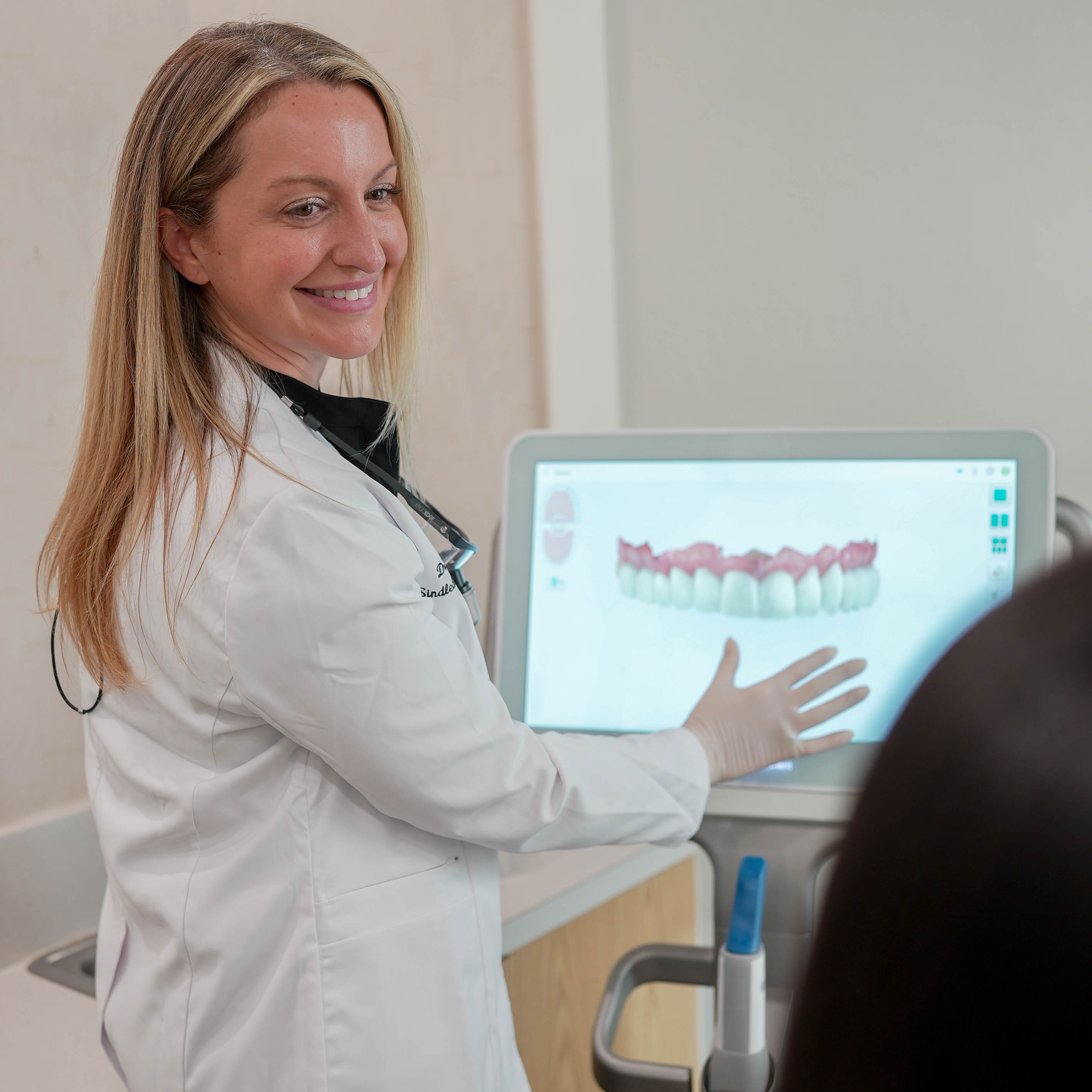 A man with a beard is wearing a white shirt and smiling with his arms crossed.