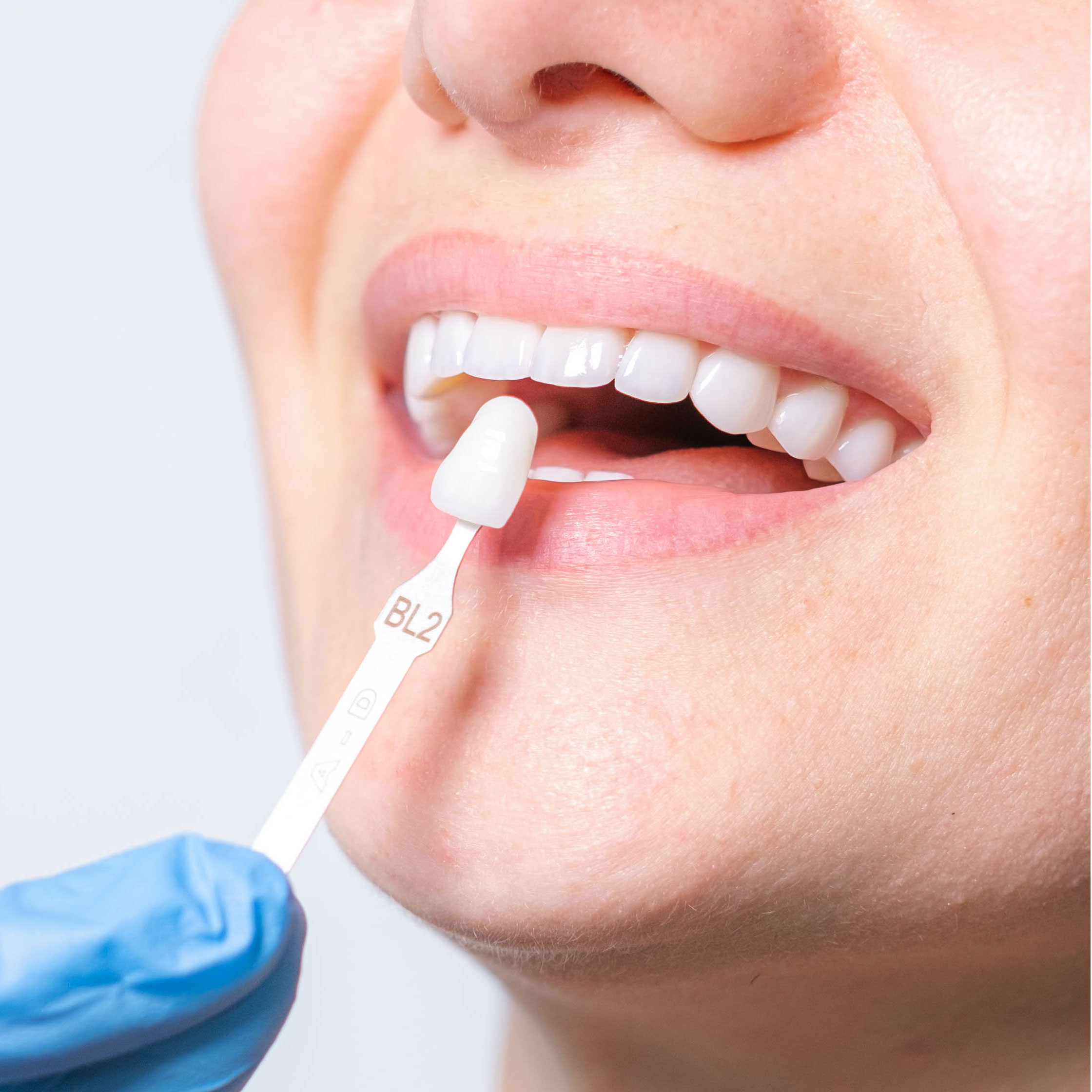 A man with a beard is wearing a white shirt and smiling with his arms crossed.