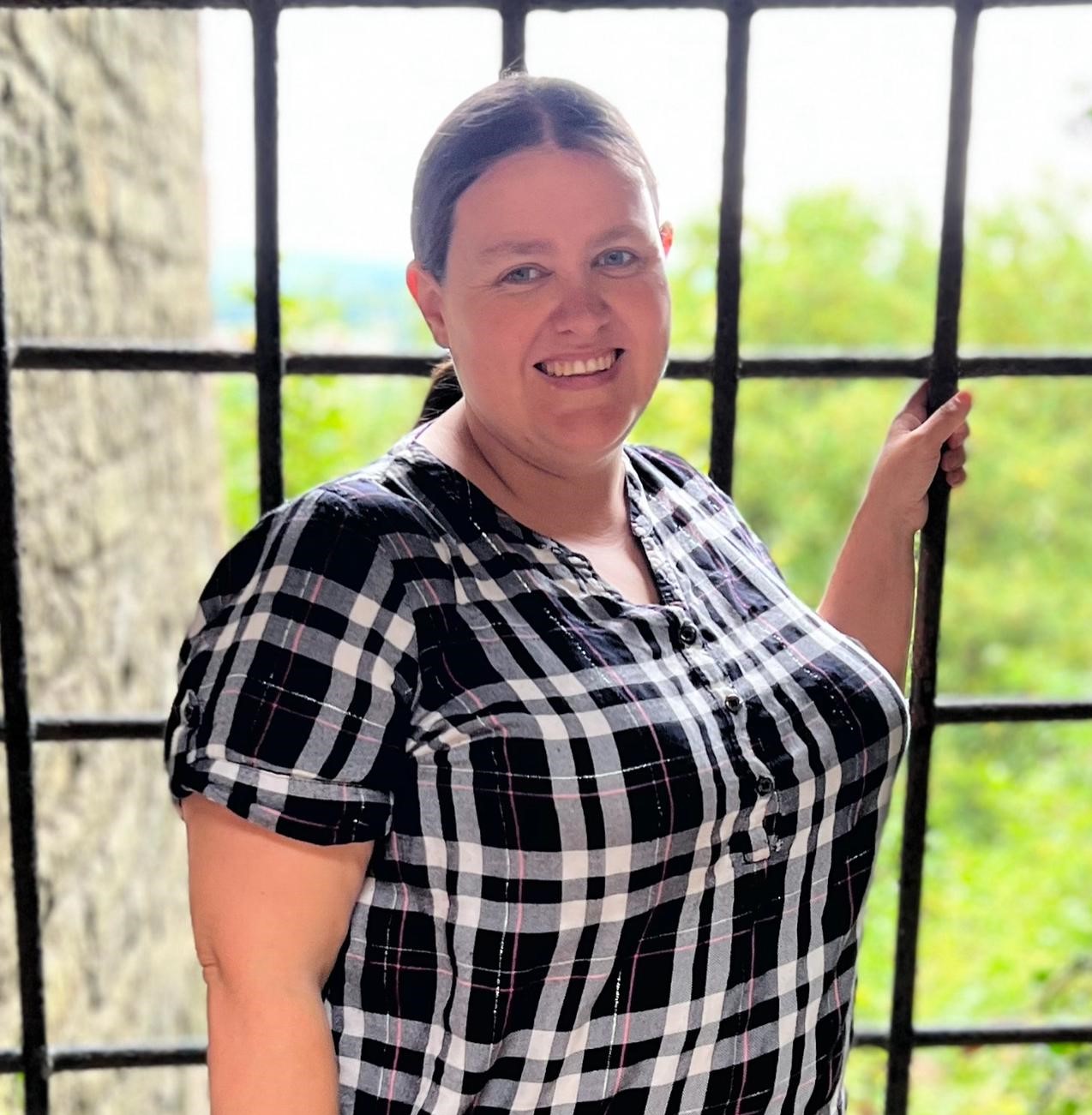 a lady called diana kilduff stood in an ancient castle window wearing a black and white check shirt