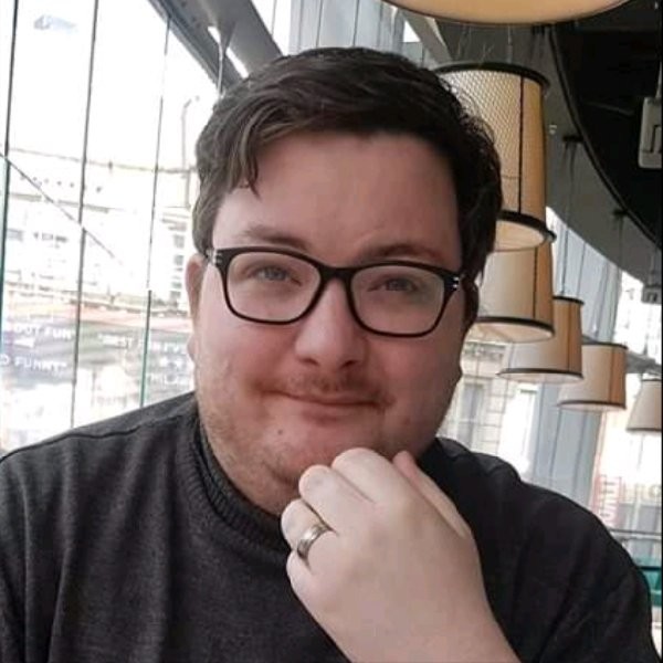 a man called dan mcgrath sat down wearing glasses and holding his hand to his chin in a restaurant