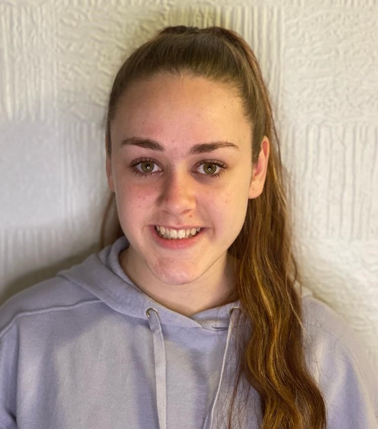 a young women called jade kilduff standing against a white wall wearing a grey hoody