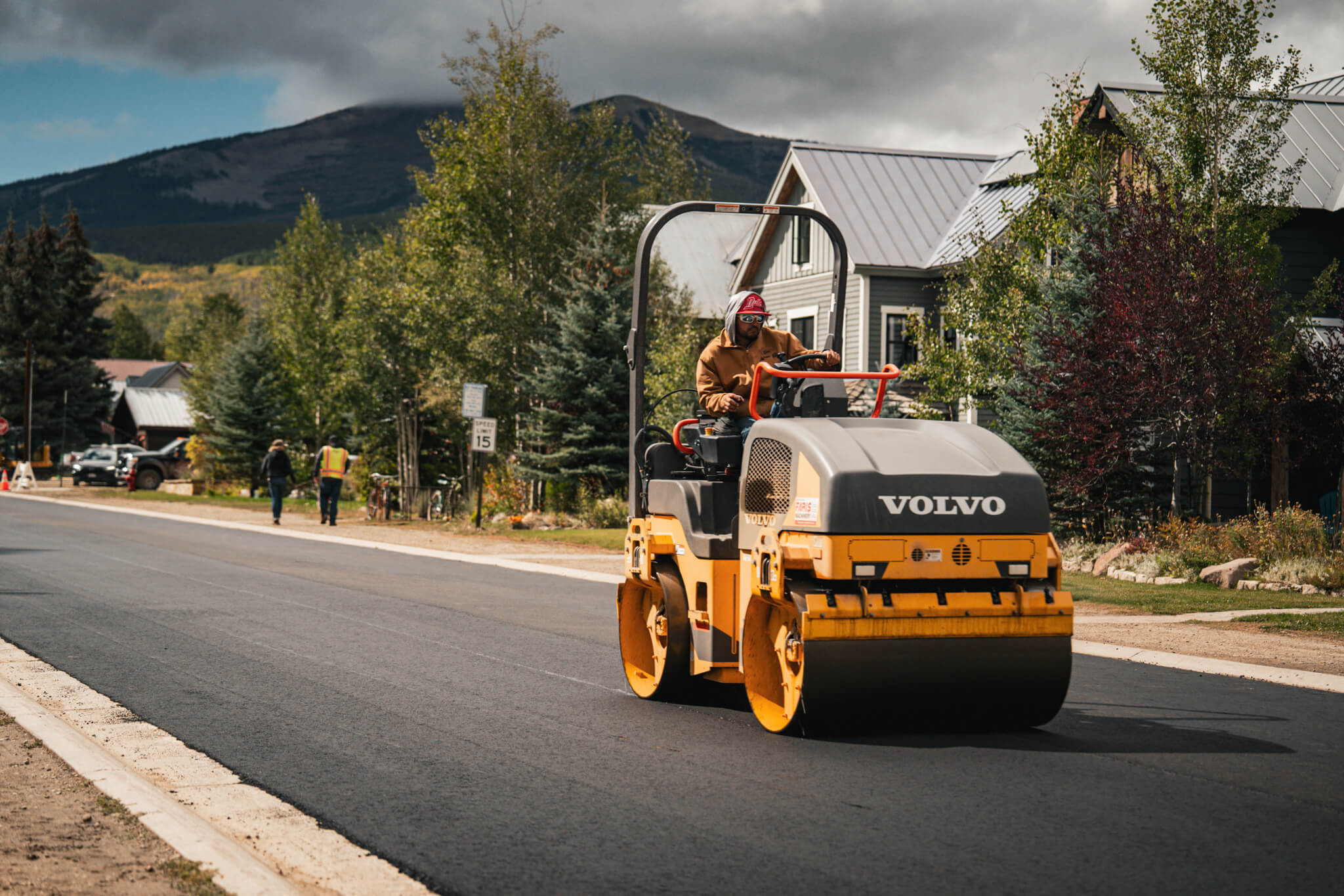 Armor Proseal's Volvo roller compactor finishing a fresh asphalt surface on a residential street in Delta, CO, showcasing professional equipment and precision paving techniques in a mountain community setting.