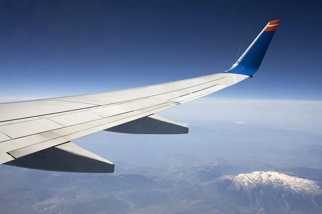 The wing of a plan over some mountains