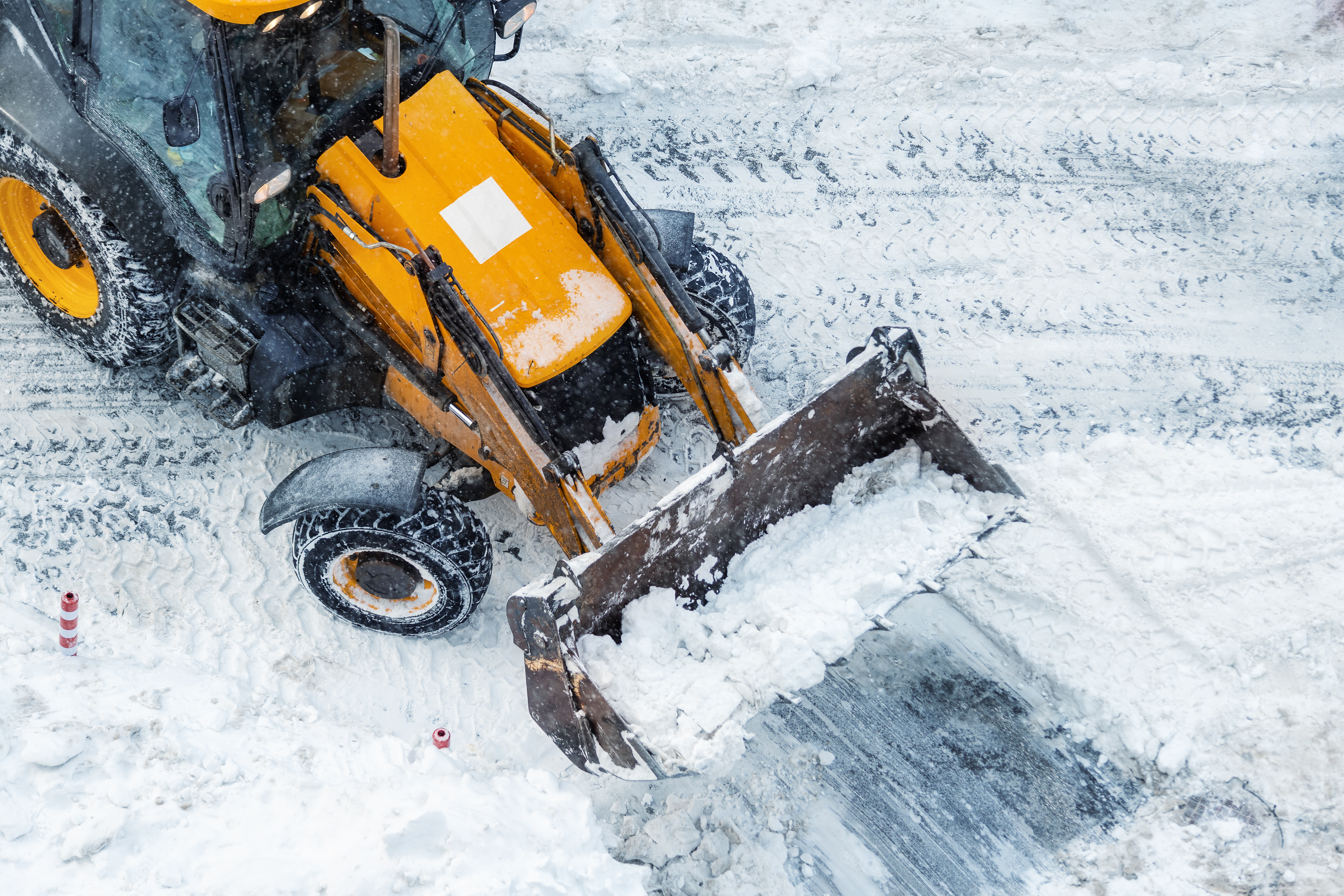 Snow removal with skid steer loader clearing a parking lot by Alpine Property Services in Colorado