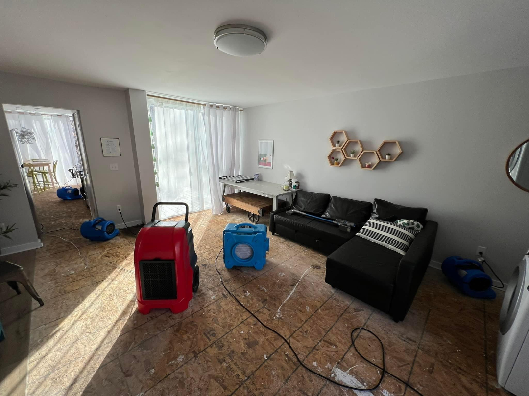 Residential living room with air movers and dehumidifiers during water damage restoration by Foothills Construction and Restoration Services in Spruce Pine, NC. Call (828) 489-3966.