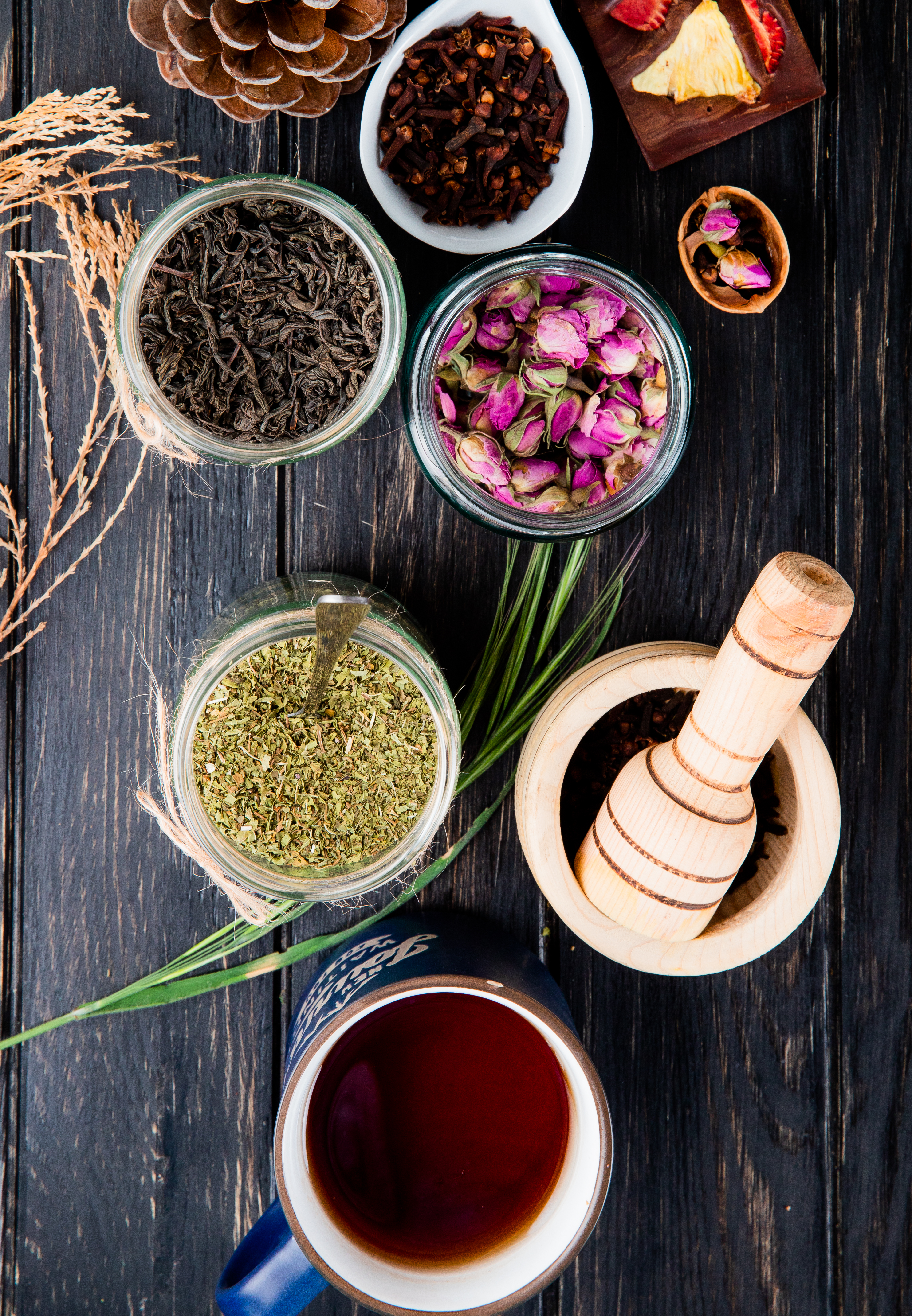 top-view-various-spices-herbs-dry-black-tea-leaves-peppermint-rose-buds-clove-spice-black-peppercorns-glass-jars-black-wood.jpg