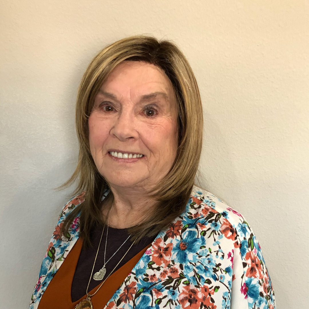 a woman wearing a black jacket and a red scarf is smiling for the camera .