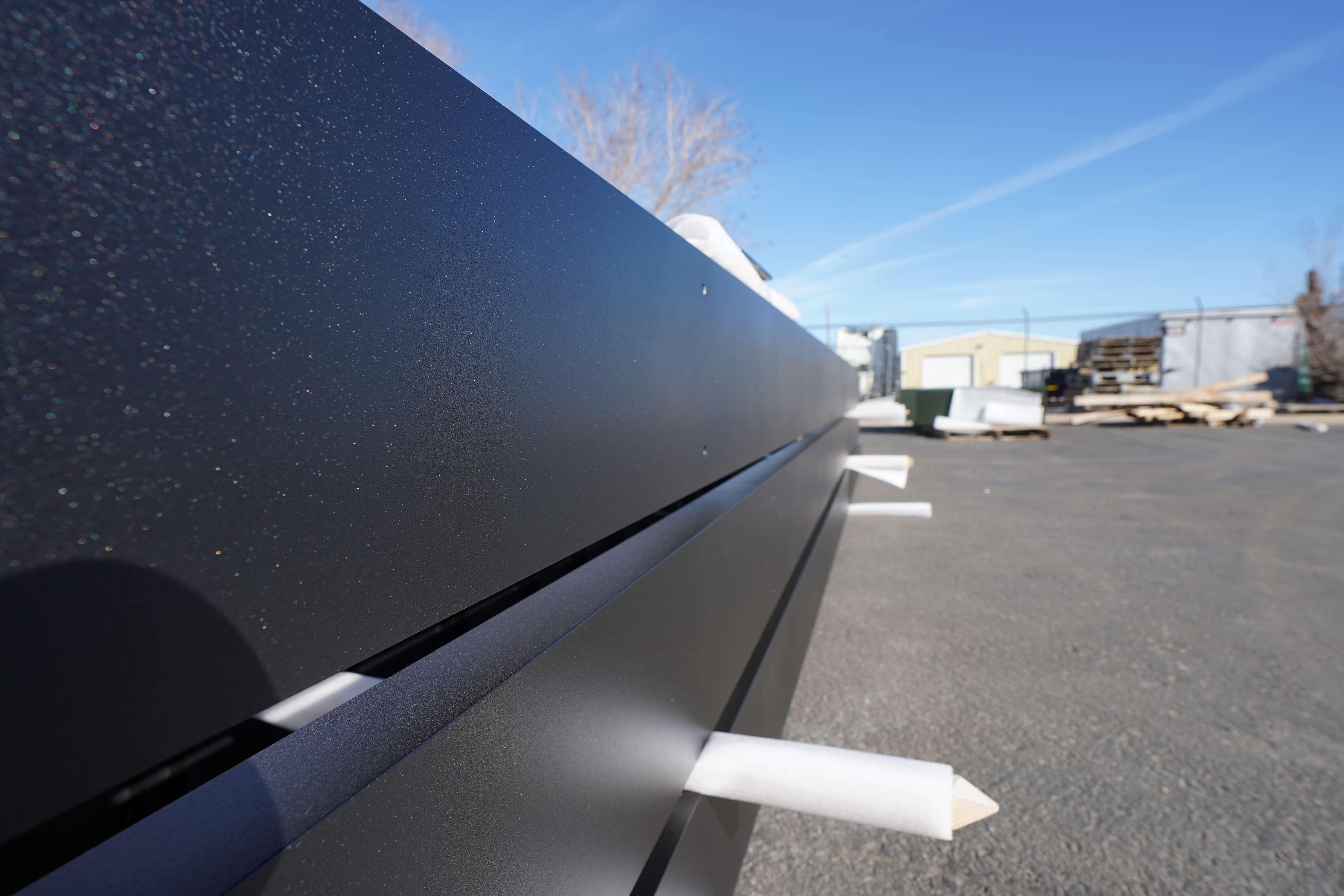 Macro shot of a smooth black powder-coated metal surface with a shimmering finish.