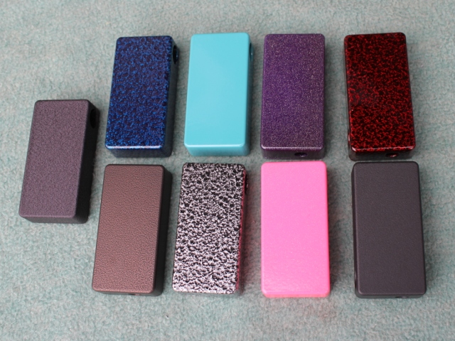 9 rectangular powder-coated metal samples displaying a variety of textures and colors, including blue, turquoise, purple, red, pink, and matte finishes, arranged in two rows against a light gray background