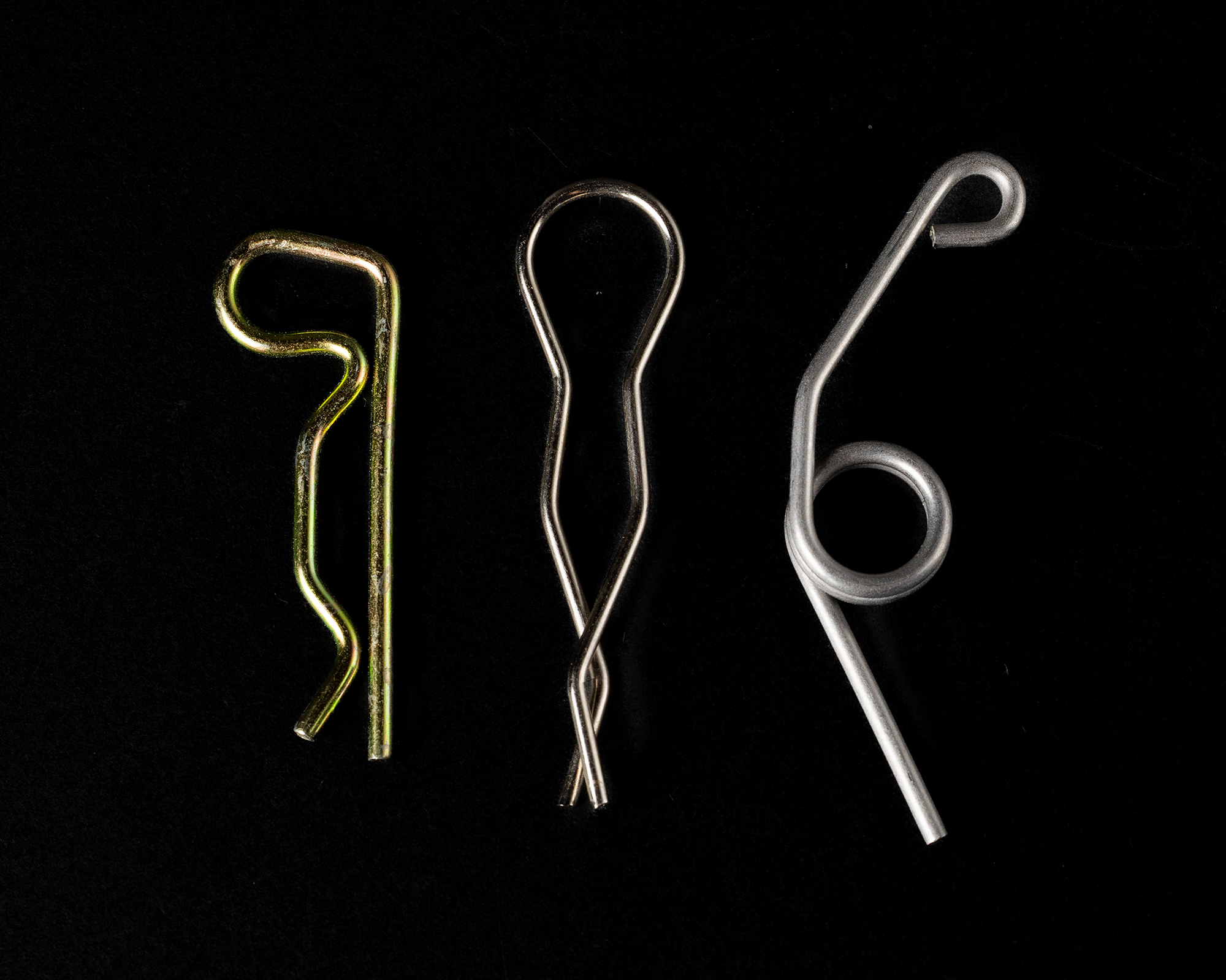 Coiled springs of varying sizes and colors on a black background, including copper, gold, black, and silver.