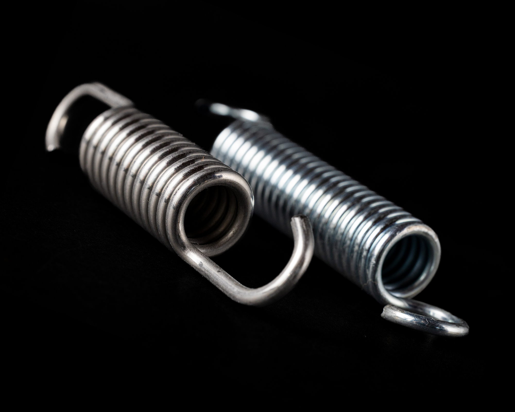 A tightly coiled metal spring against a black background.