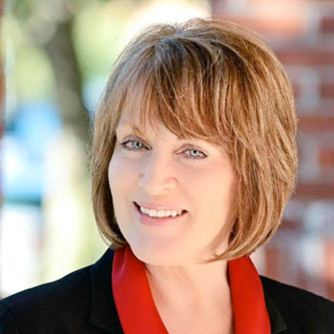 a woman wearing a black jacket and a white shirt smiles for the camera