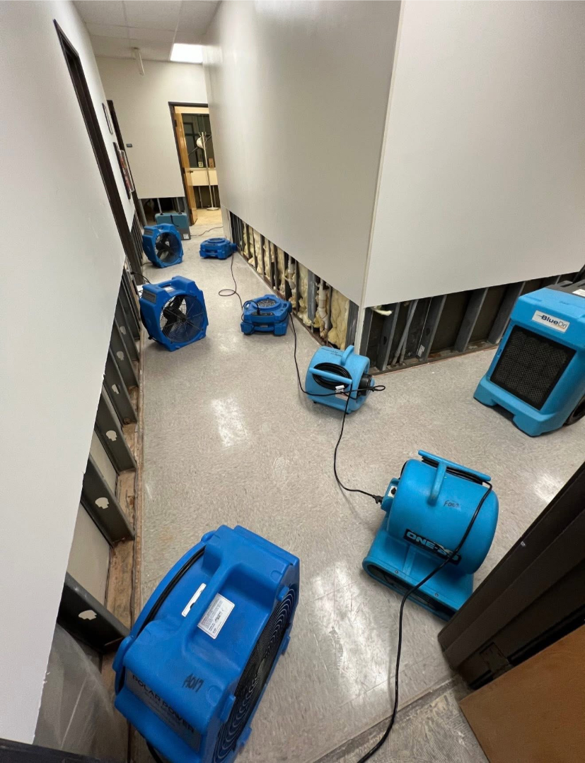 Commercial water damage restoration in progress with drying fans and dehumidifiers in a hallway by Foothills Construction and Restoration Services in Hickory, NC. Call (828) 536-4435.