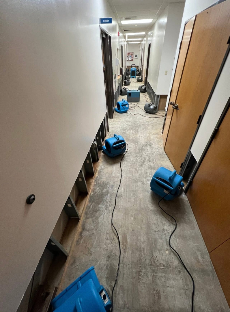 Commercial hallway with air movers and drying equipment used for water damage restoration by Foothills Construction and Restoration Services in Spruce Pine, NC. Call (828) 489-3966.