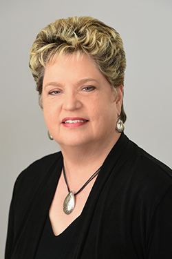 a woman wearing a black jacket and a red scarf is smiling for the camera .