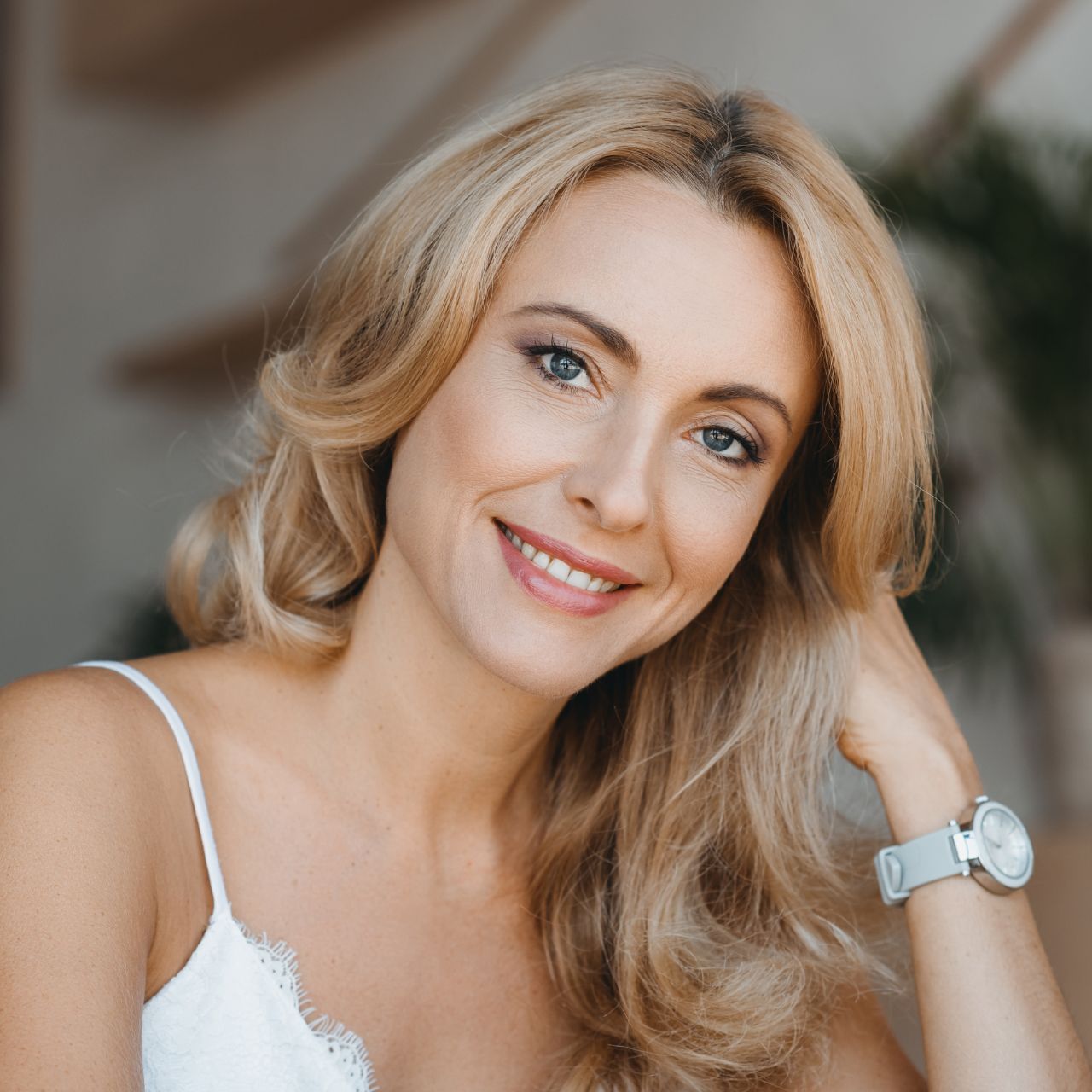 A man with a beard is wearing a white shirt and smiling with his arms crossed.