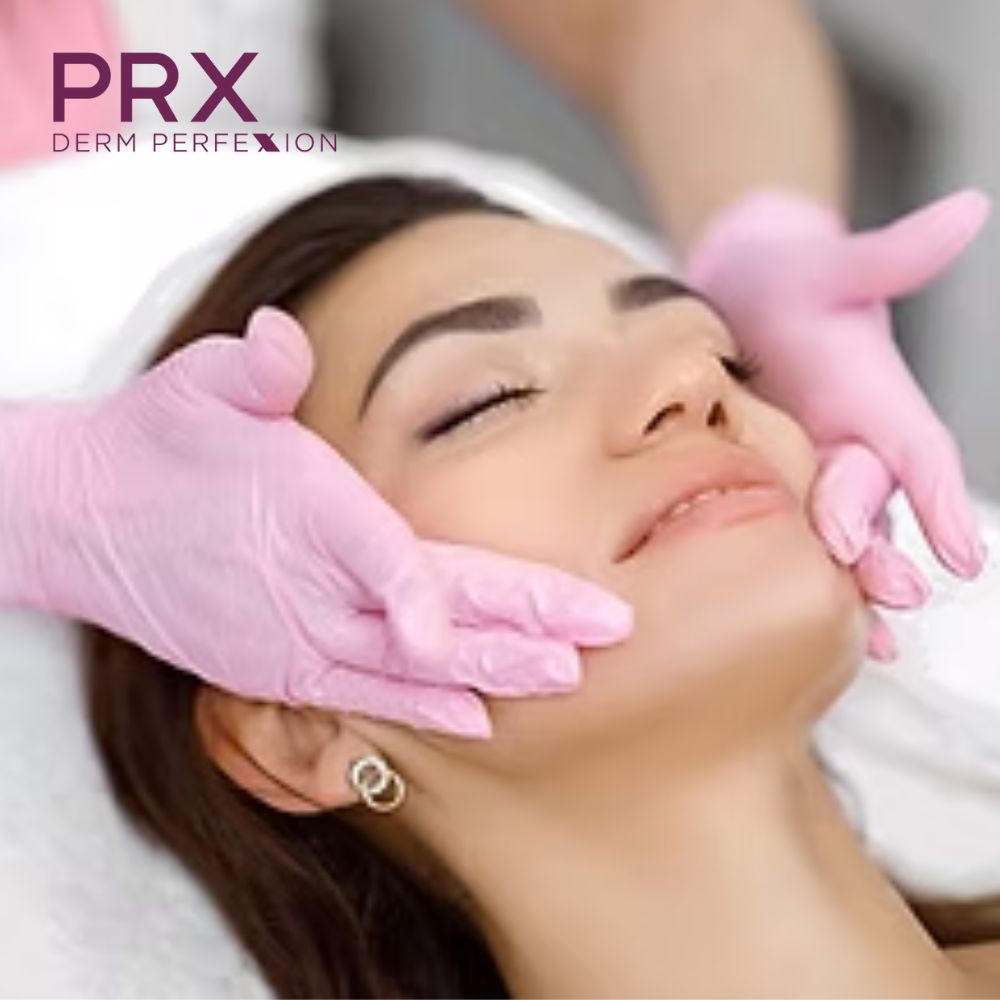 A man with a beard is wearing a white shirt and smiling with his arms crossed.