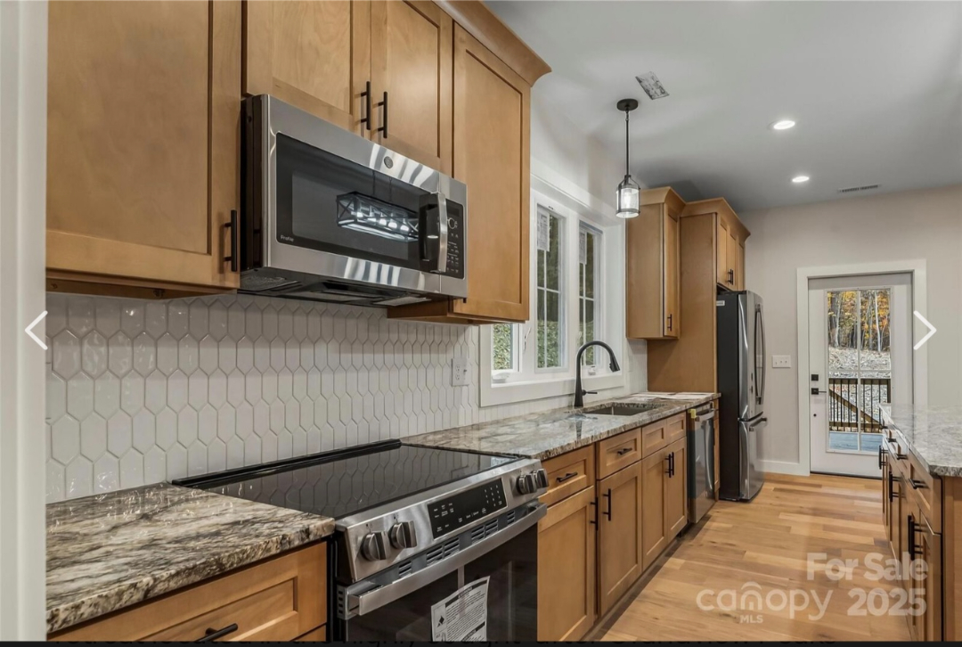 Finished kitchen renovation with new cabinets, countertops, appliances, and flooring by Foothills Construction and Restoration Services in Black Mountain, NC. Call (828) 537-4457.