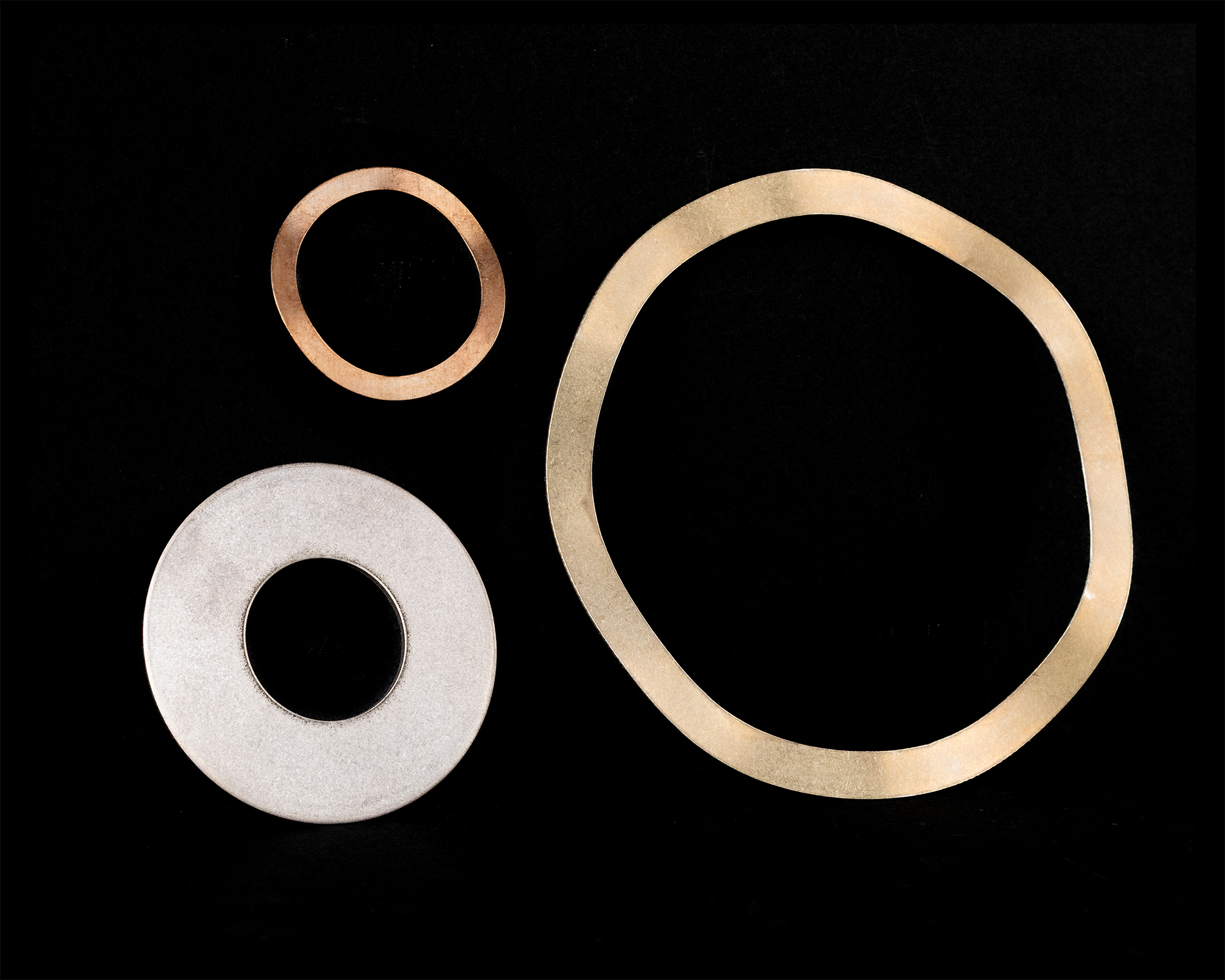 Coiled springs of varying sizes and colors on a black background, including copper, gold, black, and silver.